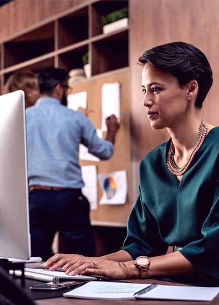 professional Woman on computer with team in background